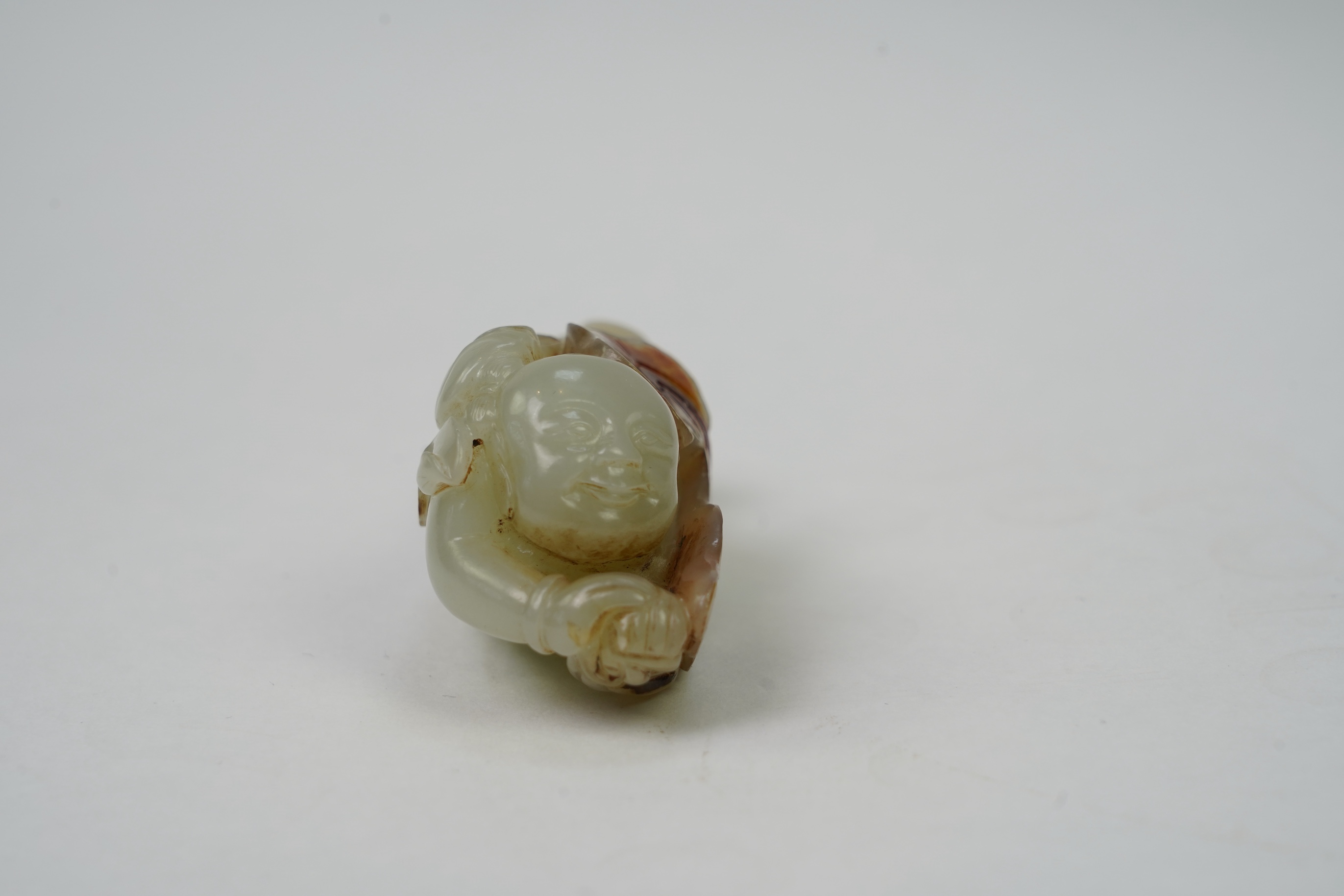 A Chinese pale celadon and russet skin jade figure of a boy and lotus